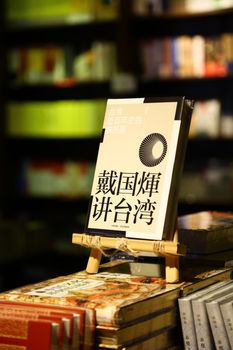 A collection of books displayed on shelves and an easel in a dimly lit bookstore.