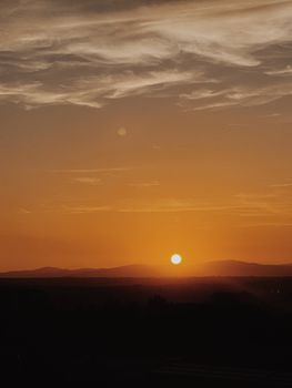 Captivating landscape with dramatic golden hour sunset over mountains and clouds.