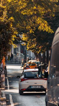 Cars on a sunlit street in İstanbul, Türkiye with trees lining the road.
