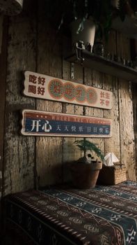 Cozy rustic interior with a potted plant and vintage signs on a wooden wall.