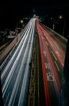 Long exposure of vibrant light trails on a busy Taipei highway at night.