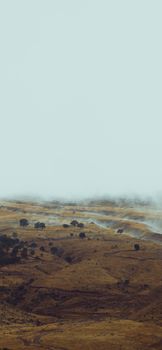 Misty hills emerge through the fog, creating a tranquil and serene landscape view.