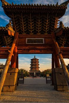 A stunning view of an ancient wooden pagoda framed by a traditional gate in Shanxi Province, China.