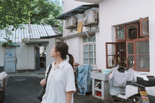 A young woman exploring an alleyway with vintage architecture on a sunny summer day.