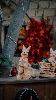 Rustic outdoor scene with animal statues and vibrant autumn leaves, showcasing fall garden charm.