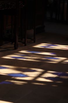 Colorful stained glass reflections create a magical pattern on a stone floor.