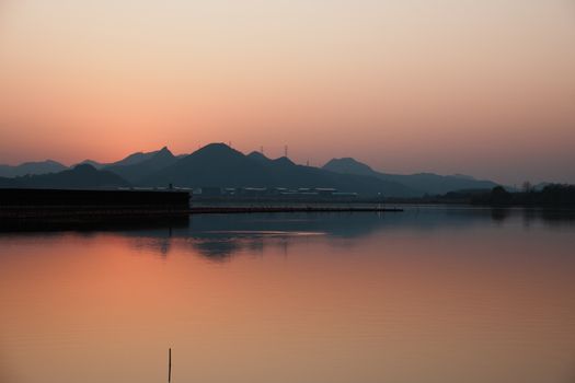Tranquil landscape of a lake reflecting mountains at sunset, creating a serene atmosphere.