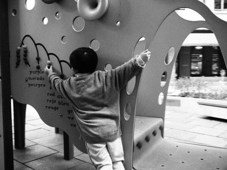A child engaging with interactive play equipment at a Hong Kong playground in black and white.