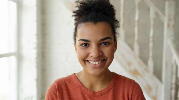 Portrait of a smiling woman indoors with natural light and a soft, neutral background.