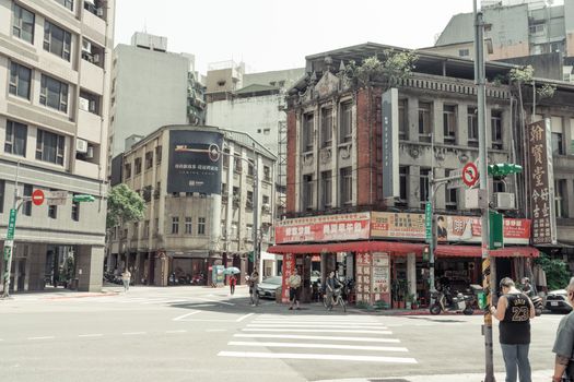 Street intersection in Taipei City with historic buildings and pedestrians, summer day.