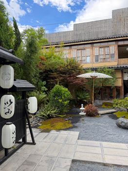 Serene traditional Chinese garden featuring lanterns and a parasol against a classic wooden building backdrop.