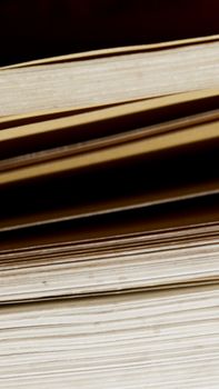 Detailed close-up shot of vertically stacked vintage hardcover books, showcasing texture and edges.