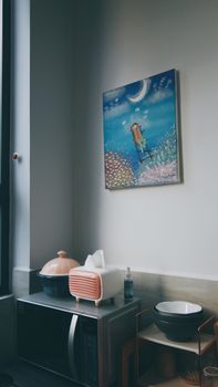 A charming kitchen corner featuring a whimsical painting and modern kitchenware under soft daylight.