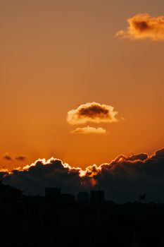 Silhouetted landscape against a vivid sunset sky with dramatic clouds and a warm atmosphere.