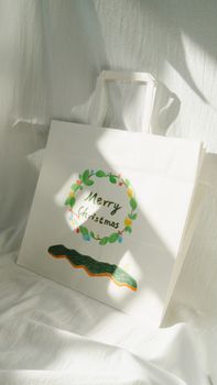 A white paper Christmas bag with festive green wreath and Merry Christmas text.