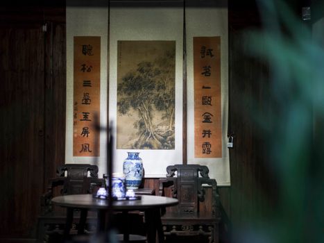 Peaceful interior features traditional Asian decor with antique furniture and scrolls, creating a serene ambiance.