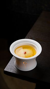 A stylish ceramic cup filled with freshly brewed tea on a dark wooden table, offering a cozy ambiance.