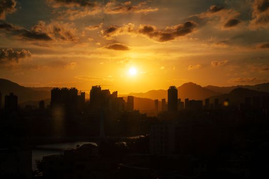 Stunning sunset over Xiamen city skyline with silhouetted skyscrapers and golden clouds.