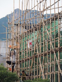 Workers on bamboo scaffolding showcasing traditional construction methods in Hong Kong.