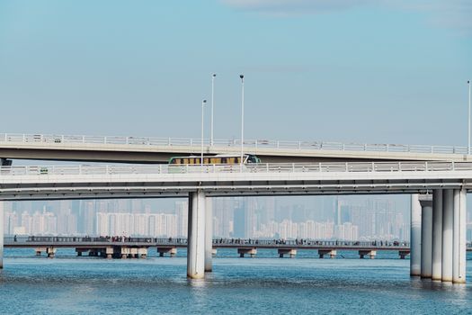 A contemporary bridge stretching over water with a city skyline in the distance.