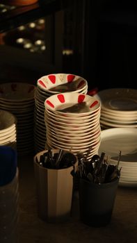 A stack of plates with a bucket of cutlery in a restaurant in Gaziantep, Türkiye.