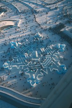 Stunning aerial shot of the Harbin Ice and Snow Festival, showcasing detailed snowflake sculpture.