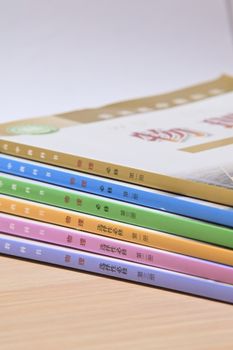 A neatly arranged stack of colorful books on a wooden surface, ideal for educational themes.