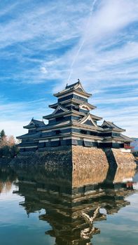 Breathtaking view of Matsumoto Castle in Japan with clear sky reflection in water.