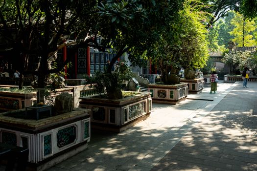 Beautiful temple garden in 佛山市, Guangdong Province, China. Sunlit path surrounded by traditional architecture and lush g