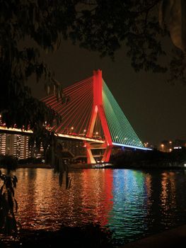 Vibrant night shot of the Guangzhou Bridge with colorful lights reflecting on the Pearl River.