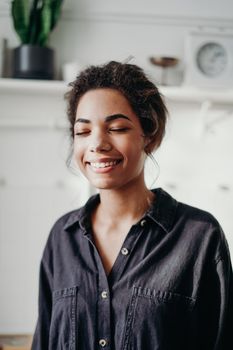 Portrait of a smiling woman indoors with closed eyes in a relaxed pose.