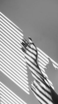 Artistic monochrome photo of hands with striped shadow patterns for creative concepts.