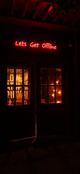 Illuminated neon sign 'Let's Get Offline' glows in a warm, cozy ambiance at night.