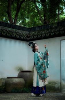 Woman in traditional Chinese costume posing in a serene courtyard.