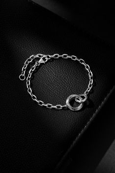 Sophisticated silver bracelet with circular pendant placed on textured black leather.